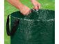Person holding a green garden waste bag against a grass background.