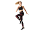 Woman in black sports bra and patterned leggings, jumping.