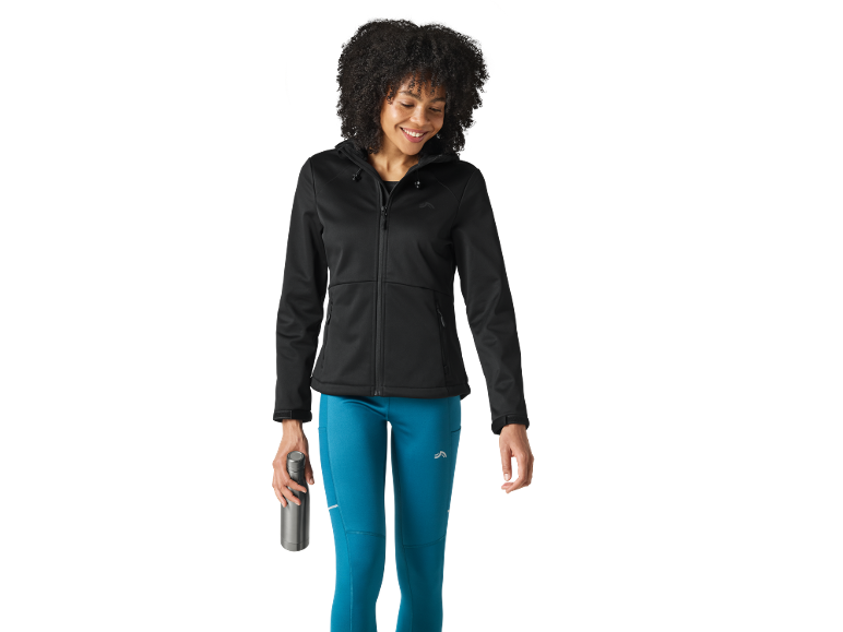 Woman in black hooded jacket and blue leggings holding a water bottle.
