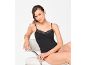 Woman in a black lace camisole sitting on a chair.