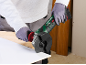 Person in gloves cutting a white tile with a cordless angle grinder.