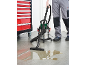 Wet/dry vacuum cleaner cleaning a liquid spill from the floor next to a tool cabinet.
