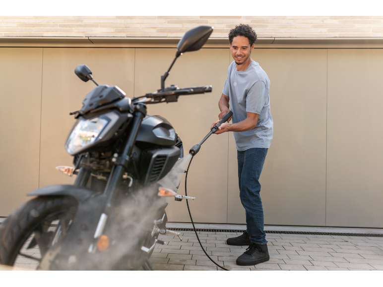 Man cleaning a motorcycle with a pressure washer