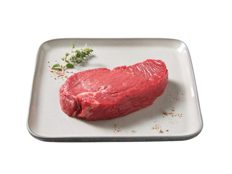 Raw beef steak with herbs and pepper on a plate.