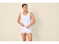Smiling man in white tank top and boxer briefs, looking to the side.