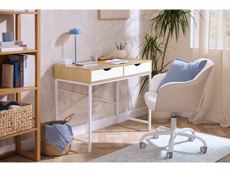 Home office with a light wood desk, white chair, and wooden bookshelf with books and baskets.