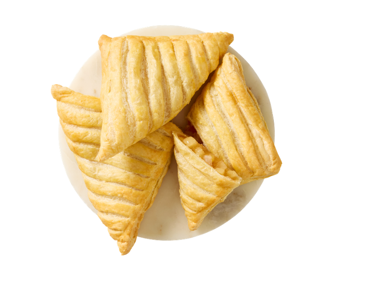 Four golden-brown apple turnovers with flaky pastry on a white plate.