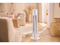 White tower fan in a living room with a sofa, table, and decorative items.