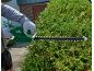 Person in gloves trimming a hedge with an electric hedge trimmer.