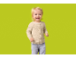 Toddler girl with blonde hair, beige cardigan, and blue jeans, smiling.