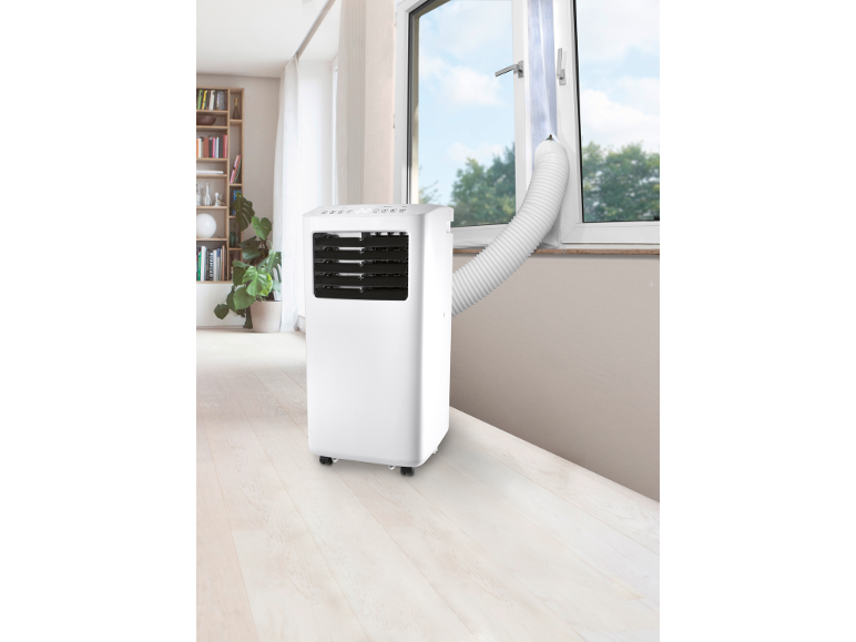 Portable air conditioner with an exhaust hose directed through a window in a bright room.