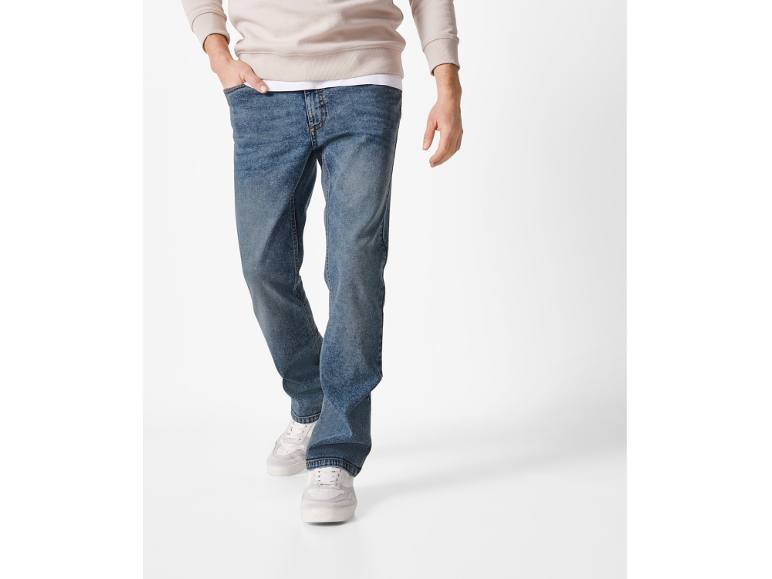 Men's blue jeans and beige sweatshirt with sneakers.