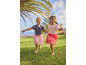 Two girls in T-shirts and tutu skirts run barefoot on the grass.