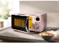 Pink microwave with an open door and a bowl of pasta on the kitchen counter.