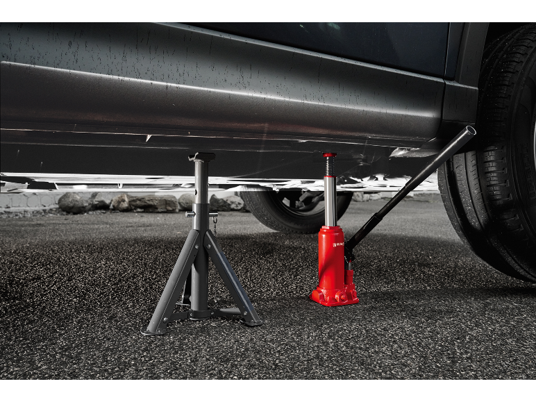 Car lifted on a jack and jack stand, on asphalt.