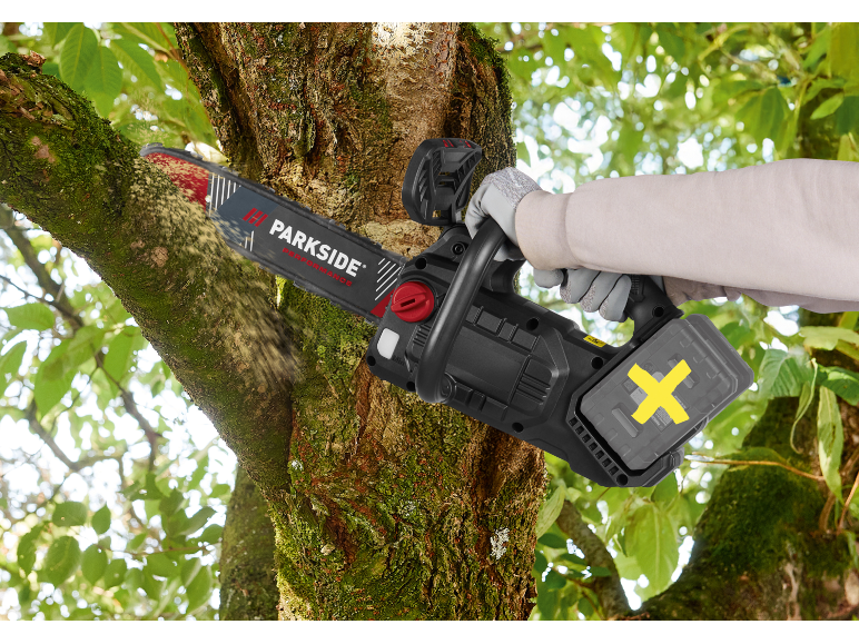 Person sawing a tree branch with a cordless chainsaw.