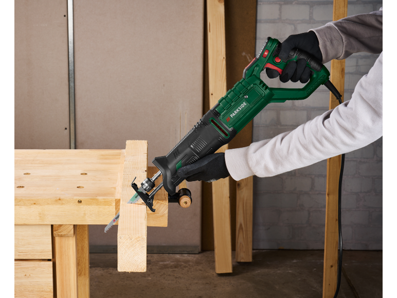 Electric reciprocating saw cutting wood on a workbench