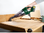 Handheld vacuum cleaner clearing wood shavings from a workbench.