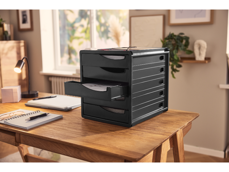 Black desk organizer with multiple drawers on a wooden desk in a home office setting.