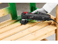 Hand holding a multi-tool with a sanding attachment, removing green paint from wooden slats.