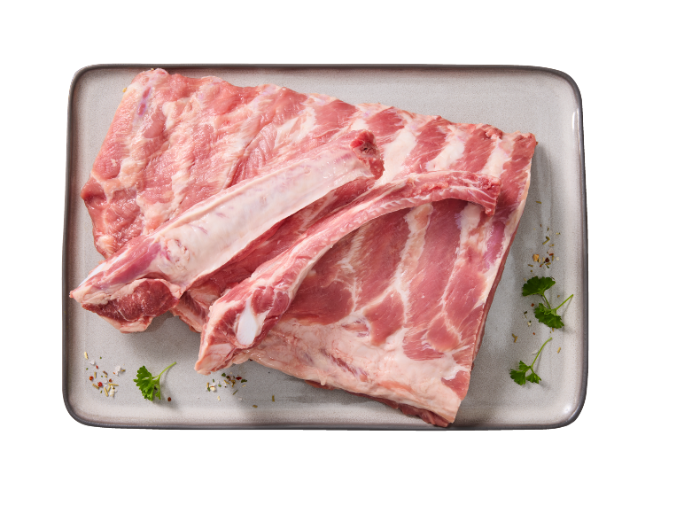 Raw pork ribs with bone on a tray, garnished with herbs and spices.