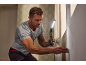 Man using an LED work light and a spatula to prepare a wall.