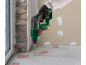 Green hammer drill drilling into a concrete floor on a construction site.