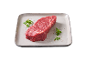 Raw beef steak on a light grey plate, garnished with herbs and spices.