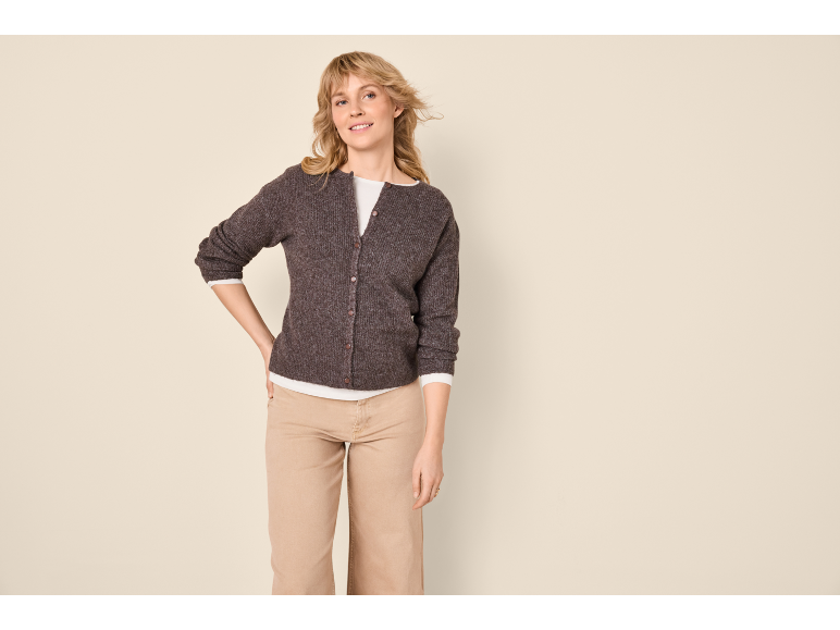 Woman in brown cardigan, white t-shirt, and beige trousers.