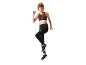 Woman in a patterned sports bra and black leggings, mid-jump.