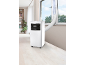 Portable air conditioner with an exhaust hose directed through a window in a bright room.