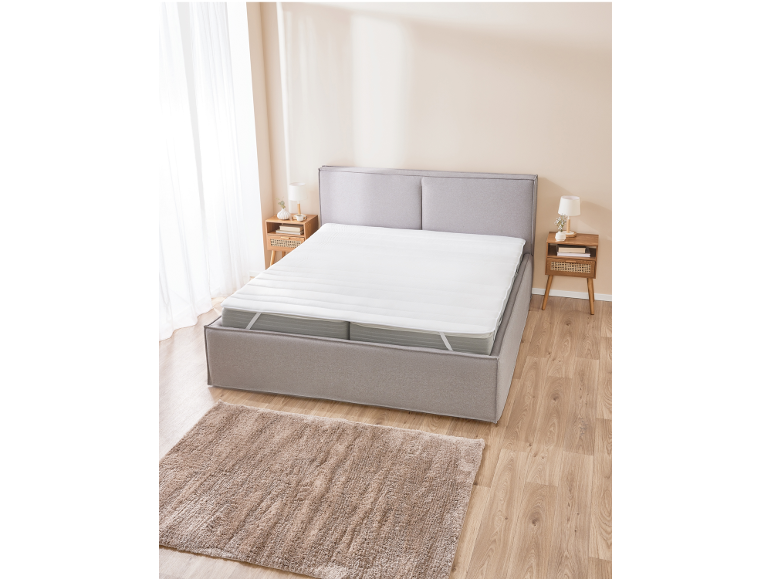 Bright bedroom with a grey bed, white mattress topper, and a fluffy rug.