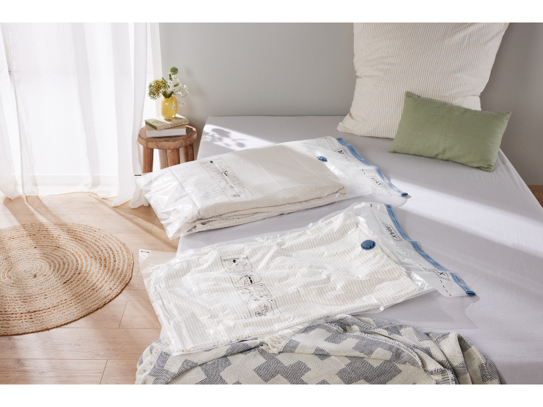 Vacuum storage bags with bedding on a bed in a bright bedroom.