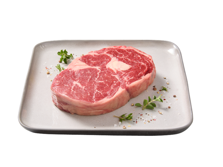 Raw beef steak with herbs and spices on a plate.