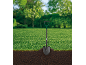 Shovel in a freshly dug hole in a green lawn with trees in the background.