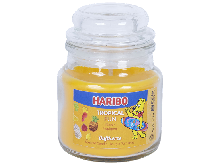 Yellow scented candle in a glass jar with a 'Tropical Fun' label and a surfing bear.