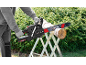 Man cutting a wooden log with a chainsaw on a sawhorse in the garden.