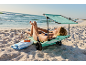 Woman relaxing on a beach trolley with a sunshade, next to a towel and sunscreen.