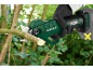 Cordless pruning shears in a hand, cutting a branch.