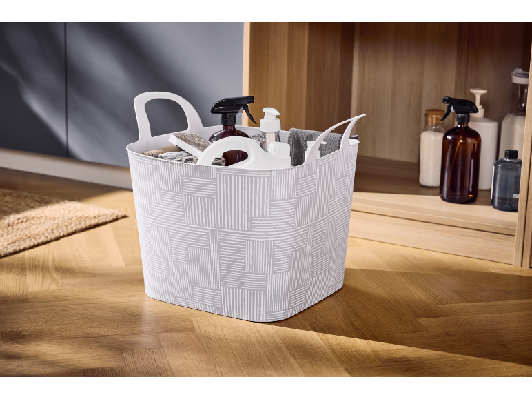 White basket with cleaning products and accessories on a wooden floor.