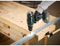 Cordless drill boring into a metal profile on a carpenter's workbench.
