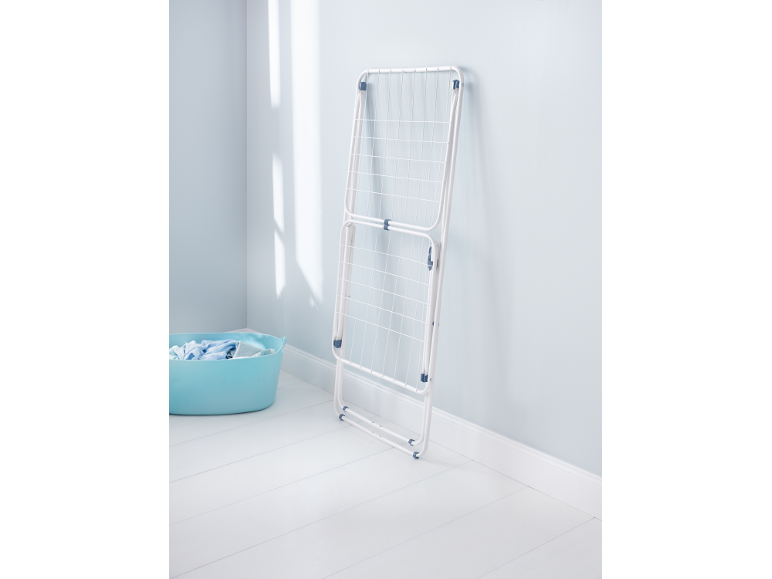 White clothes drying rack and blue laundry basket in a bright room.