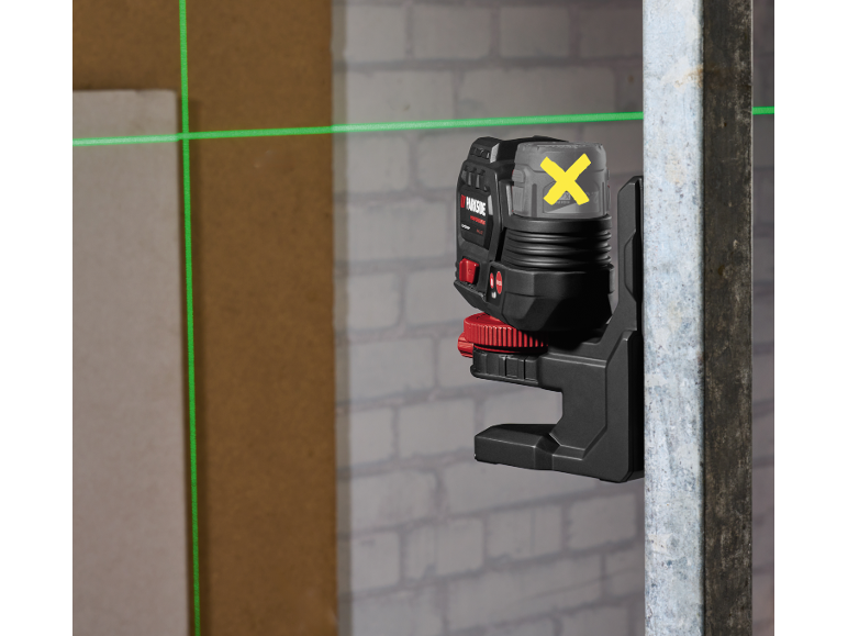 Green laser level projecting horizontal and vertical lines on a construction site.