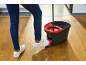 Person using a mop bucket and mop with a pedal wringer on a wooden floor.