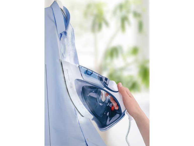 Steam iron ironing a blue shirt, held in hand.
