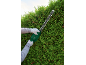 Gloved person trimming a hedge with an electric hedge trimmer.