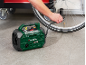 Man inflating bicycle tire with green portable compressor.