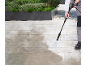 Person cleaning garden tiles with a pressure washer.