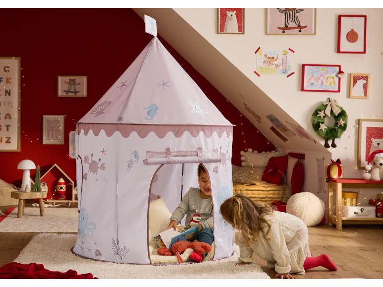 Two children playing with a marine-themed play tent in a Christmas-decorated room.
