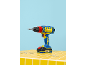 Blue and yellow cordless drill on yellow tiles with screws.